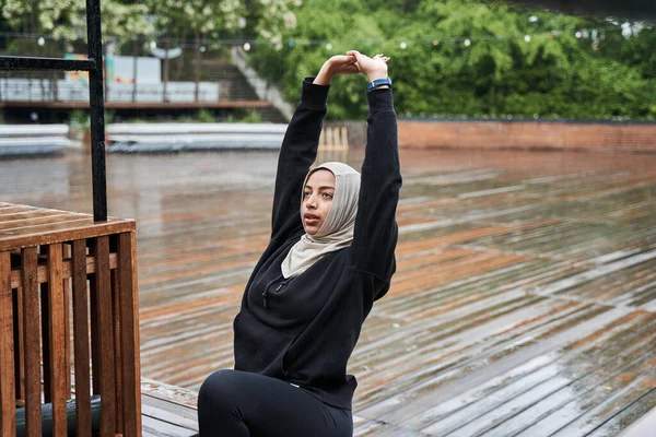 Mujer con pañuelo en la cabeza haciendo gimnasia en el parque lluvioso de primavera —  Fotos de Stock
