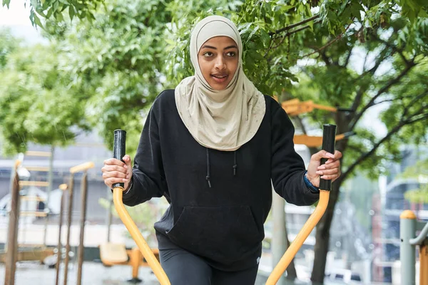Mujer con ropa deportiva musulmana estiramiento y entrenamiento en el equipo especial —  Fotos de Stock
