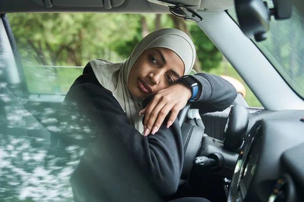 Kobieta patrząca przez okno i trzymająca głowę za kierownicę — Zdjęcie stockowe