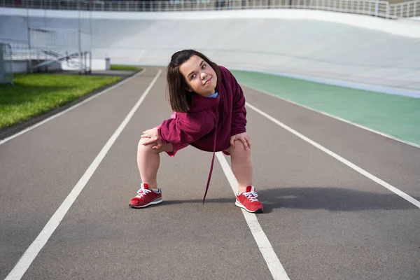 Карликовая женщина медленно разогревается перед тренировкой на стадионе — стоковое фото