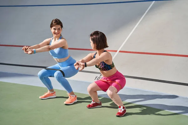 Midget woman wearing sports wear exercising in outdoor arena with her best friend