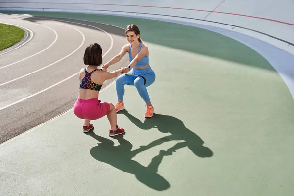 Donne che si guardano mentre si tuffano e si accovacciano sull'erba dello stadio — Foto Stock