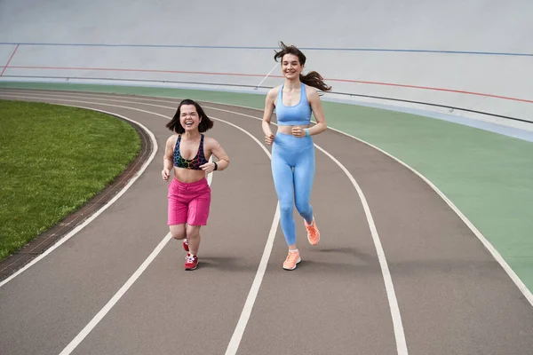 Vrouwen in sportkleding joggen op hardloopbaan in het Stadsstadion in de zonnige ochtend — Stockfoto