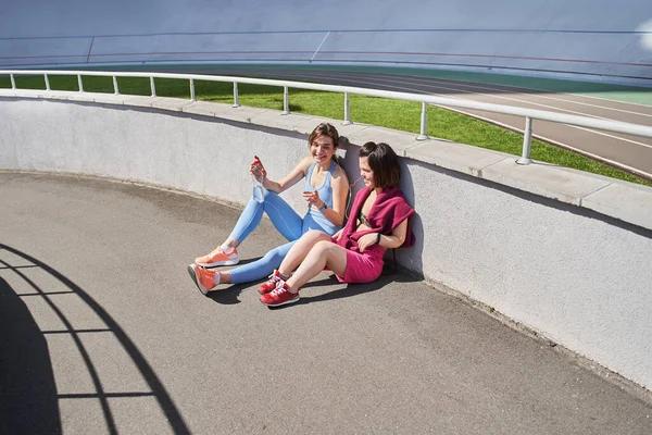 Chicas en ropa deportiva relajarse después de un entrenamiento o correr y tener una conversación — Foto de Stock