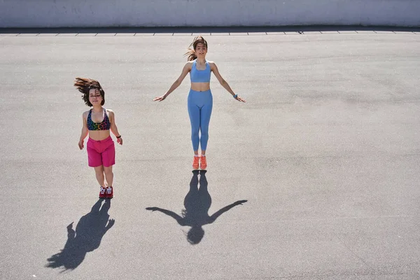 Две разноплановые девушки прыгают на треке на стадионе во время утренней тренировки — стоковое фото