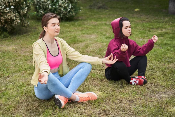 Woman sitting cross-legged near her best friend, practicing yoga and enjoying meditation
