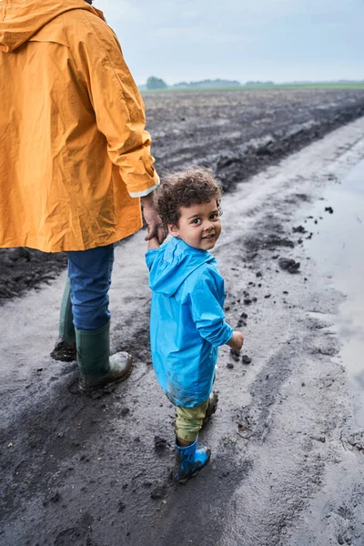 Мальчик в болотистых резиновых сапогах смотрит в сторону, наслаждаясь ходьбой — стоковое фото