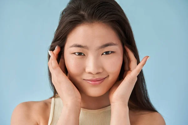 Asiática de pelo largo mujer poniendo sus manos en su cara y posando — Foto de Stock