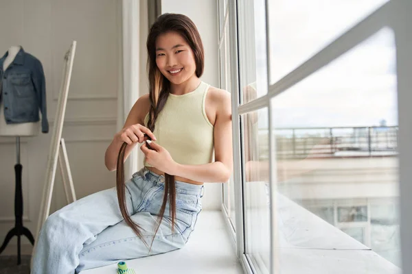 Woman looking at the camera with wide smile while combing her hair — Stock Photo, Image