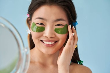 Stüdyoda aynanın önünde dikilirken makyaj bantları yapıştıran bir kadın.