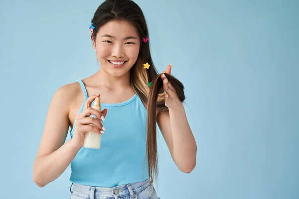 Vrouw met haar conditioner terwijl ze naar de camera kijkt en spray vasthoudt — Stockfoto