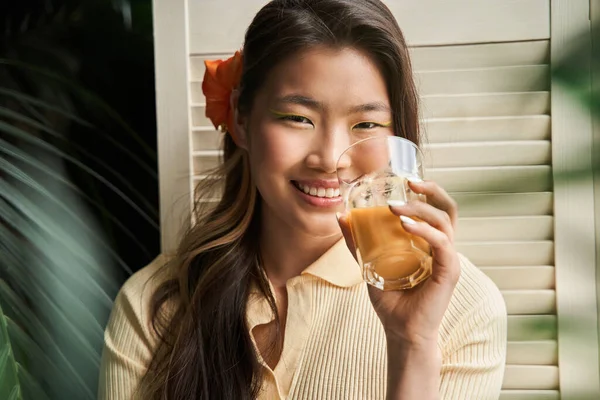 Meisje met een glas sinaasappel- of wortelsap en een glimlach op de camera — Stockfoto