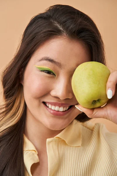 Vrouw met creatieve make-up verbergen haar oog achter de appel terwijl poseren — Stockfoto