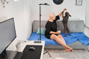 Kel kadın aktif Fransız bulldoguyla oynuyor.