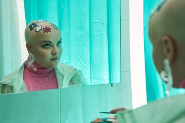 Kel kadın dış görünüşünü değerlendirirken ciddi ciddi yansımasına bakıyor.