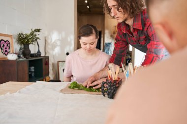 Heykeltıraş, Down sendromlu tatlı bir kıza yaprak rahatlatma taklidi yapmayı gösteriyor.