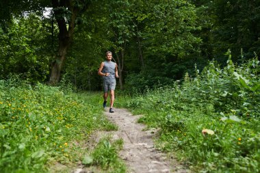 Yaz parkında koşan ve vücudunu formda tutmaya çalışan bir adam.