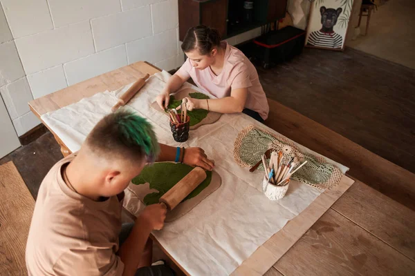 Pareja de adolescentes con síndrome de Down sentados y haciendo impresión de la textura de la hoja — Foto de Stock