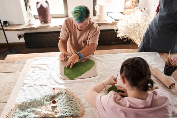 Pareja de adolescentes con síndrome de Down sentados y haciendo impresión de la textura de la hoja —  Fotos de Stock