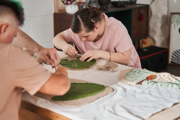 Meisje maakt aandachtig indruk van de bladtextuur op de klei in de masterclass — Stockfoto