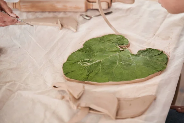Folha verde que põe na futura chapa de textura de impressão na argila — Fotografia de Stock