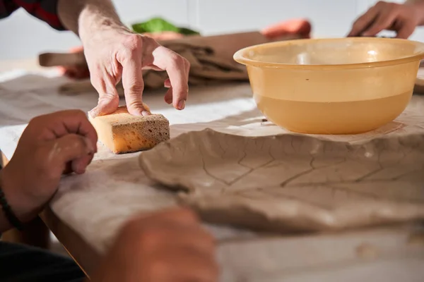 Beeldhouwer zit aan tafel met jongen met speciale behoeften en legt hem uit — Stockfoto