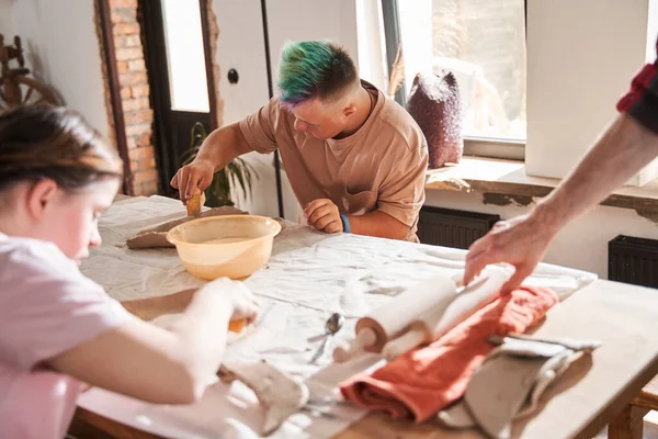 Menino com cabelo colorido fazendo prato da argila na mesa — Fotografia de Stock