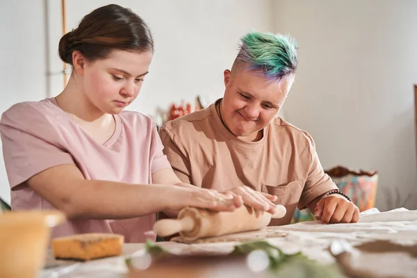 Meisje met down syndroom rollen met de pin verschillende vormen van de klei — Stockfoto