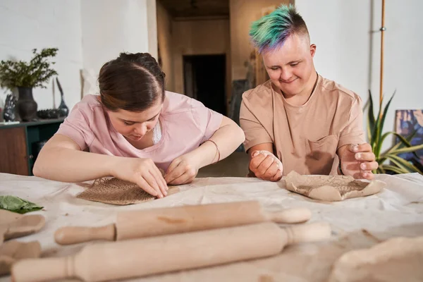 Jongen met speciale behoeften afgewerkt zijn bord van de klei en kijken naar zijn vriendin — Stockfoto