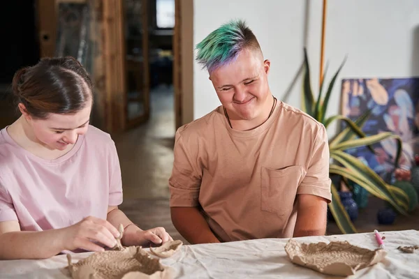 Niño con síndrome de Down sonriendo felizmente y mirando los platos — Foto de Stock