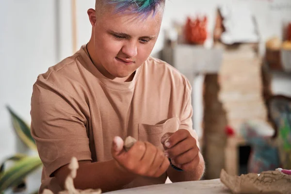 Niño con el pelo de color que sostiene la arcilla en las manos y examinarlo durante la clase magistral — Foto de Stock