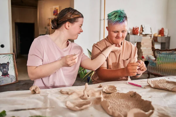 Meisje aanraken van het gezicht van haar vriend met gekleurd haar, terwijl hij met klei — Stockfoto