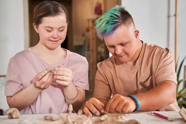 Een paar van de down syndrome mensen die zich gelukkig voelen en werken met klei — Stockfoto