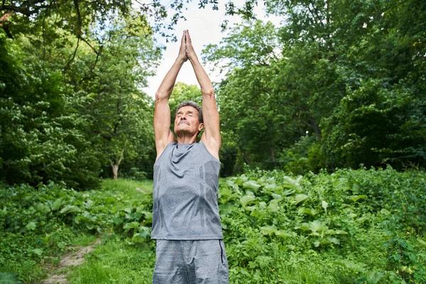 Muž protahování, cvičení a pocit klidu při trávení času kolem letní přírody — Stock fotografie
