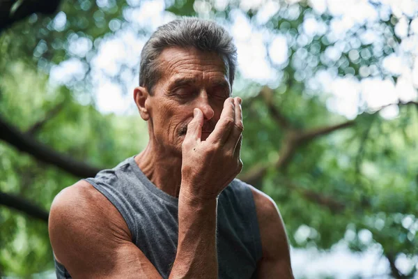 L'uomo tiene gli occhi chiusi e fa esercizio respiratorio mentre chiude la narice con il dito — Foto Stock