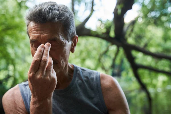 Uomo anziano che pratica la respirazione yoga pranayama mentre seduto al tappeto all'aperto — Foto Stock