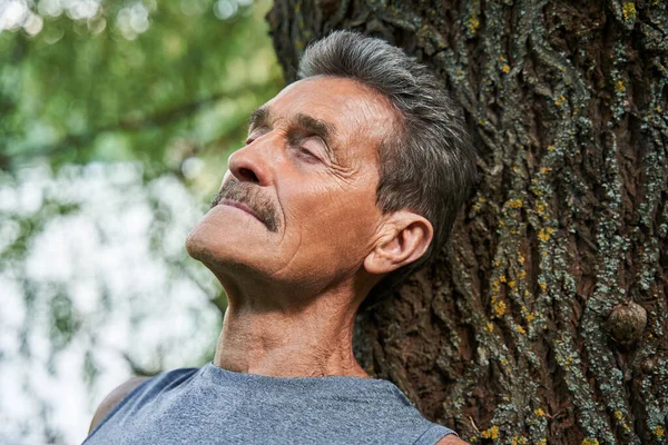 나무 줄기에 눈을 감고 앉아 좋은 에너지 를 흡수하는 사람 — 스톡 사진