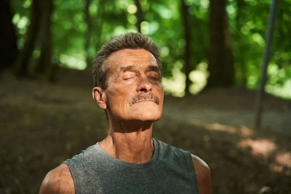 Uomo in piedi presso la foresta intorno agli alberi e ha chiuso gli occhi mentre riposava — Foto Stock