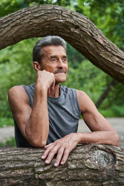 Elderly man standing near the tree and looking away with pleasure — Stock Photo, Image