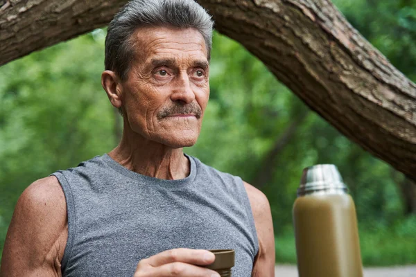 Uomo guardando lontano e tenendo in mano tazza di tè caldo mentre godendo della bevanda aromatica — Foto Stock