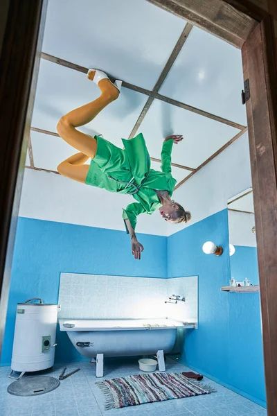 Fashion model met groene jas poseren aan het plafond in de badkamer — Stockfoto