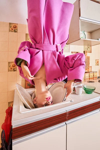 Vrouw dragen roze outfit staande hoofd over hakken aan het plafond — Stockfoto
