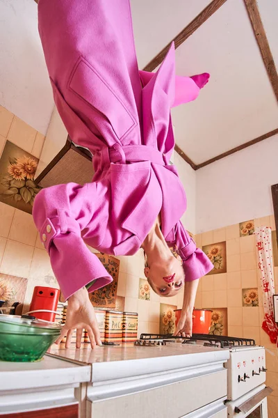 Elegante modello femminile in piedi a testa in giù presso la cucina vintage durante la posa — Foto Stock