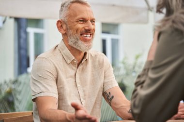 Man smiling toothy while chatting with his wife during the romantic date