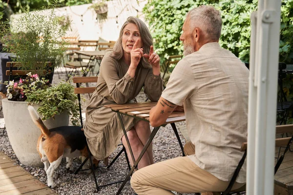 Woman telling something to her lovely man while sitting at the summer cafe — Stockfoto