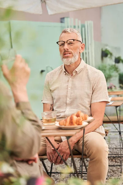 Serious man telling something to his wife during the cup of tea at the romantic date — Stockfoto