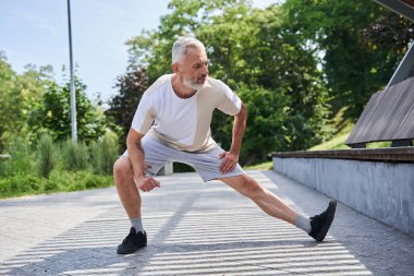 Mature man stretching body and feeling flexible while exercising at the park
