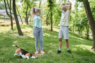 Spouses wearing protective masks looking at each other while having morning exercises