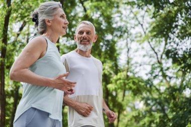 Senior couple wearing sportswear running at the park in morning at the fresh air