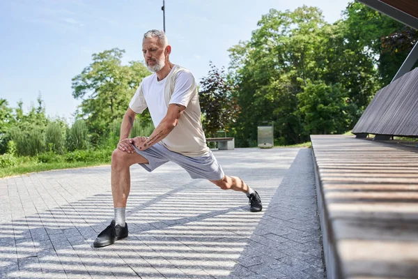 Літній чоловік робить легені під час тренувань у літньому парку на свіжому повітрі — стокове фото